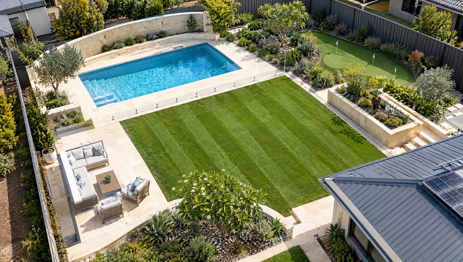 Aerial view of a finished Perth backyard by Paradise Limestone, showing the pool, limestone walls, lawn, alfresco, putting green and garden beds
